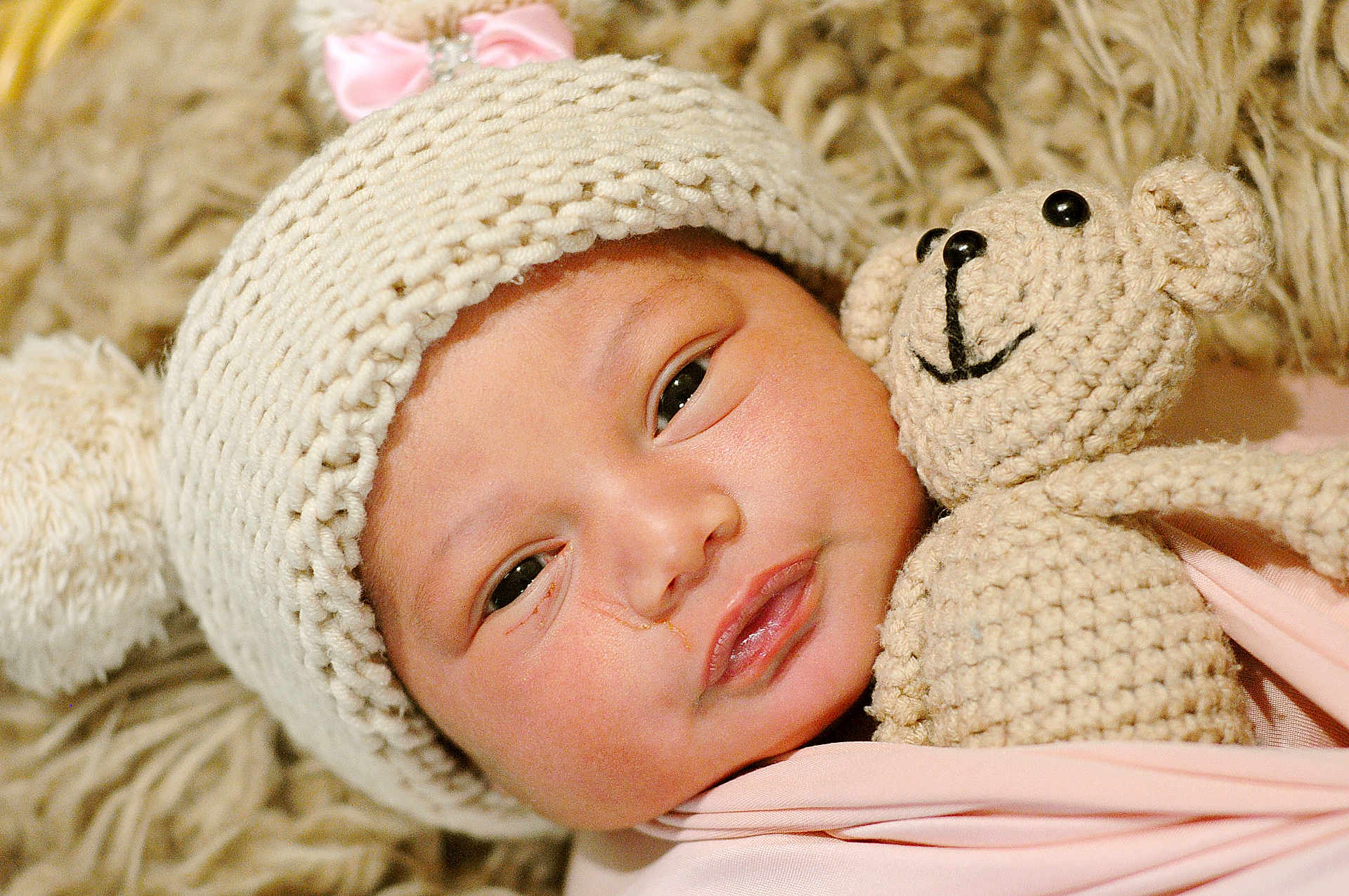 Anila joined the competition — help win amazing prizes! baby, infant, knitted_hat, pink_bow, crocheted_toy, teddy_bear, blanket, soft_texture, sleepy, closeup, cute, child, face, newborn, cozy, warm, wrapped, portrait, indoor, comfort