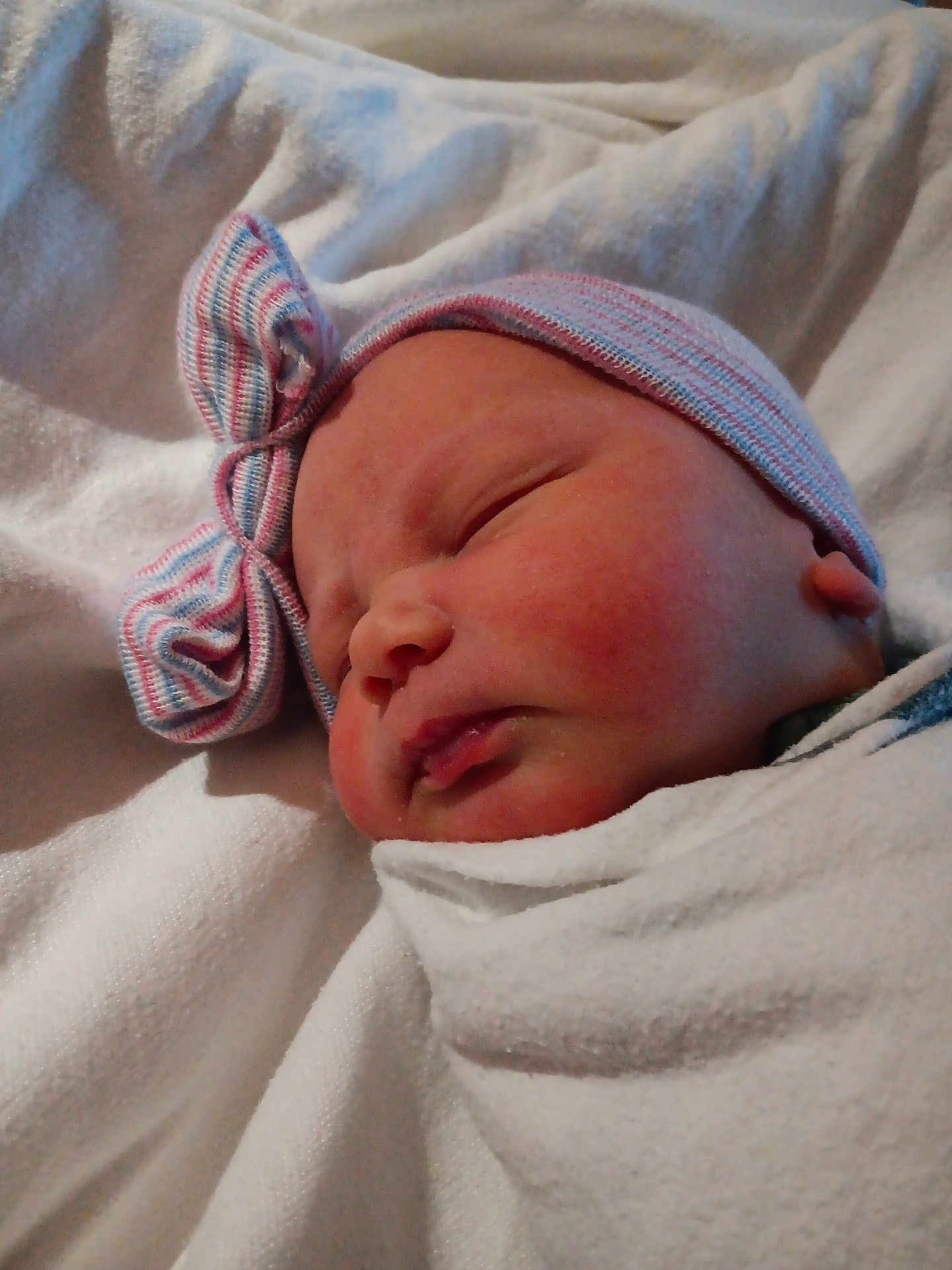 Jaylyn is registered to the contest to win money with this photo: baby, newborn, infant, swaddled, blanket, hat, bow, sleeping, face, cheek, hospital_blanket, closeup, portrait, peaceful, soft_texture, skin, newborn_cap, bedding, resting, head