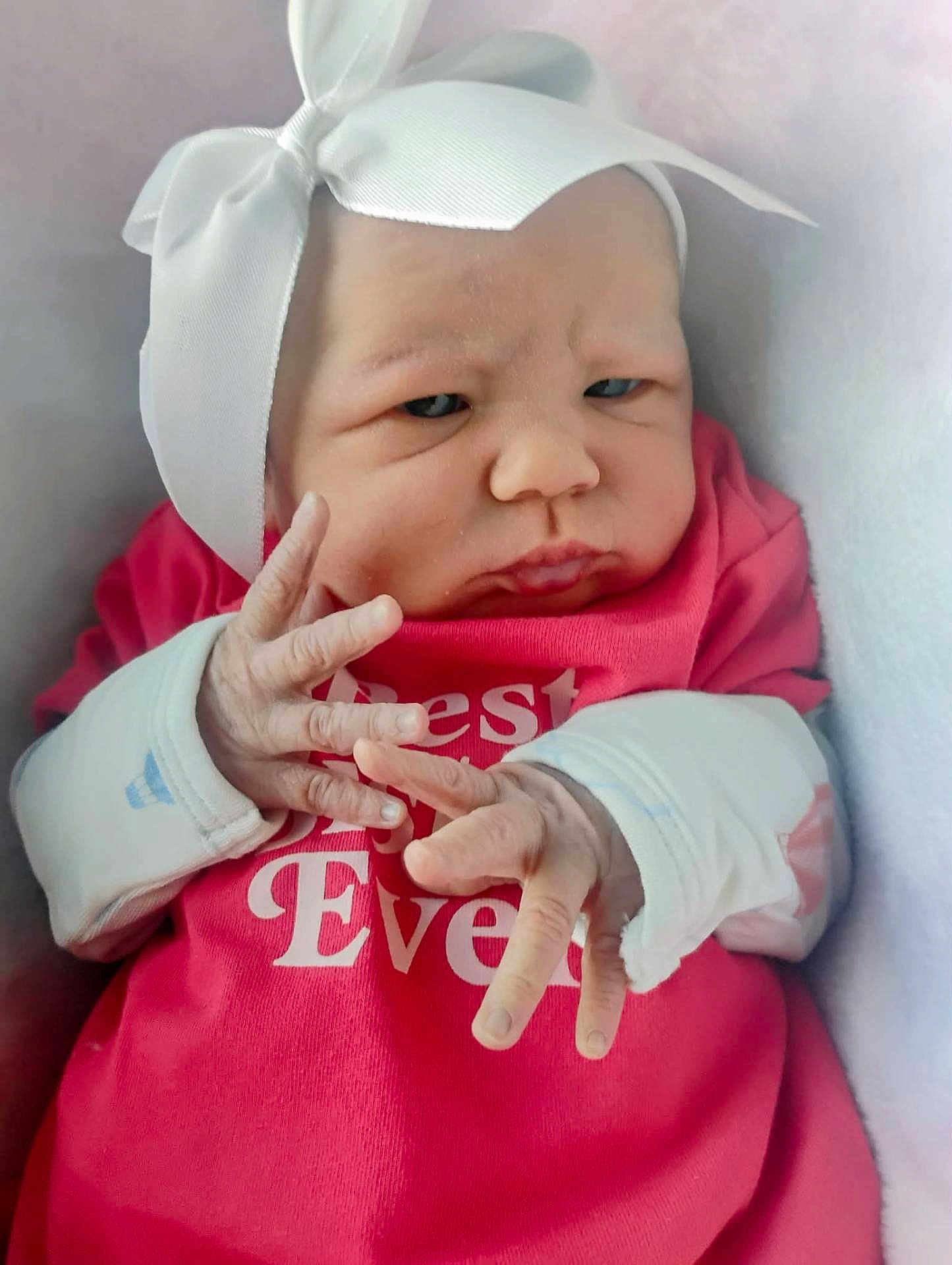 Jaylyn is registered to the contest to win money with this photo: baby, infant, headband, bow, red_shirt, hands, fingers, expression, face, closeup, blanket, cozy, newborn, person, cute, soft_lighting, indoors, portrait, child, clothing