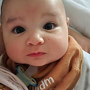 Ilyann participe au concours pour gagner de l'argent avec cette photo : baby, infant, close_up, face, wide_eyes, pacifier, bib, brown_bib, clothing, person, cartoon_print, shirt, dog_cartoon, indoor, bed, slippers, soft_focus, skin, cute, portrait