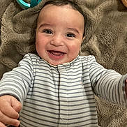 Kaïs participe au concours pour gagner de l'argent avec cette photo : baby, infant, smile, laughing, striped_pajamas, onesie, blanket, hands, face, cheeks, brown_eyes, toys, playmat, lying_down, portrait, closeup, happy, cozy, skin, cuddly