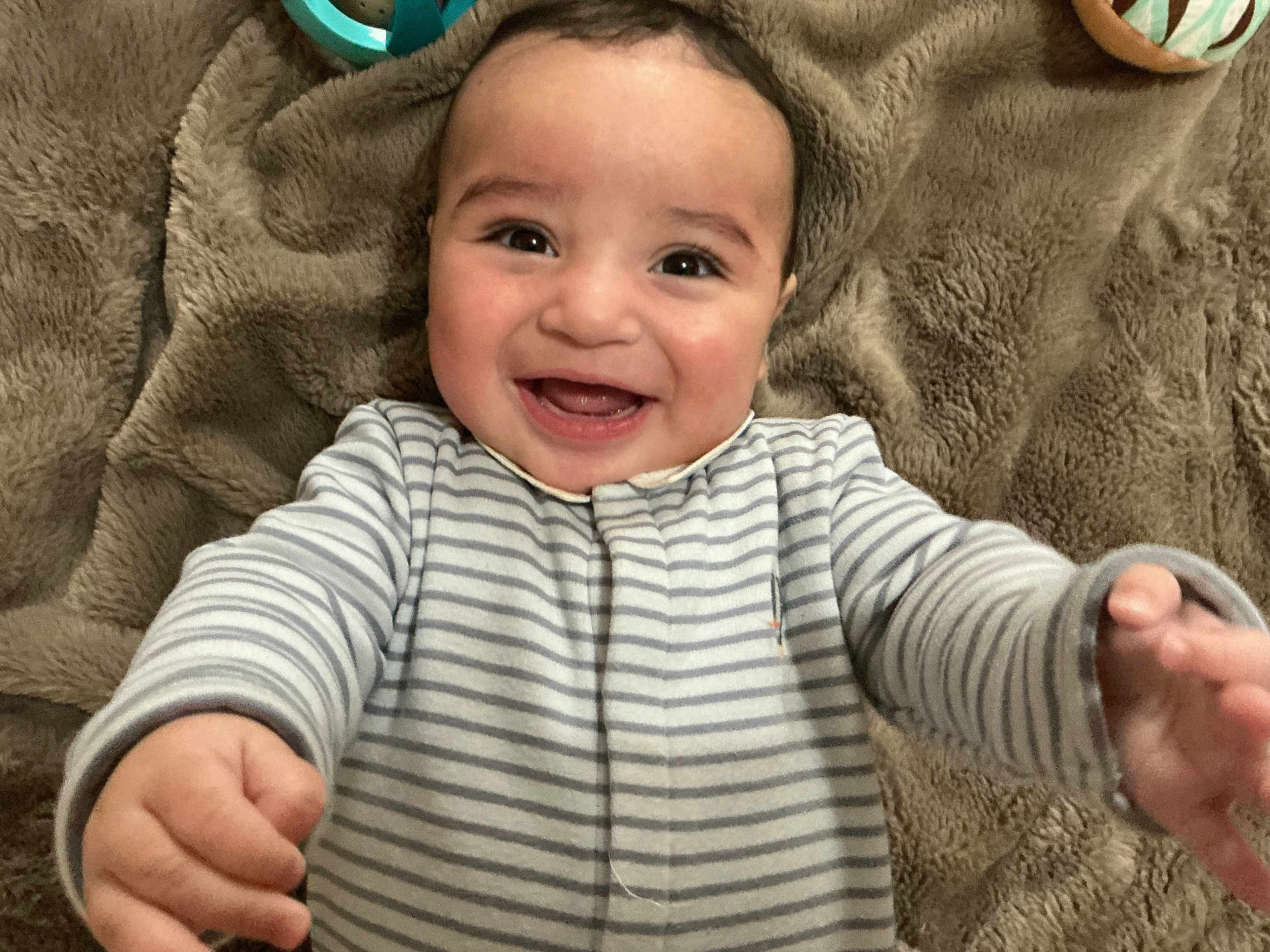 Kaïs participe au concours pour gagner de l'argent avec cette photo : baby, infant, smile, laughing, striped_pajamas, onesie, blanket, hands, face, cheeks, brown_eyes, toys, playmat, lying_down, portrait, closeup, happy, cozy, skin, cuddly
