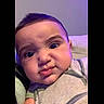 baby, infant, child, portrait, face, eyes, serious_expression, close_up, sitting, indoor, cushion, sofa, clothing, striped_shirt, purple_lighting, cozy, head, cheeks, photography, home