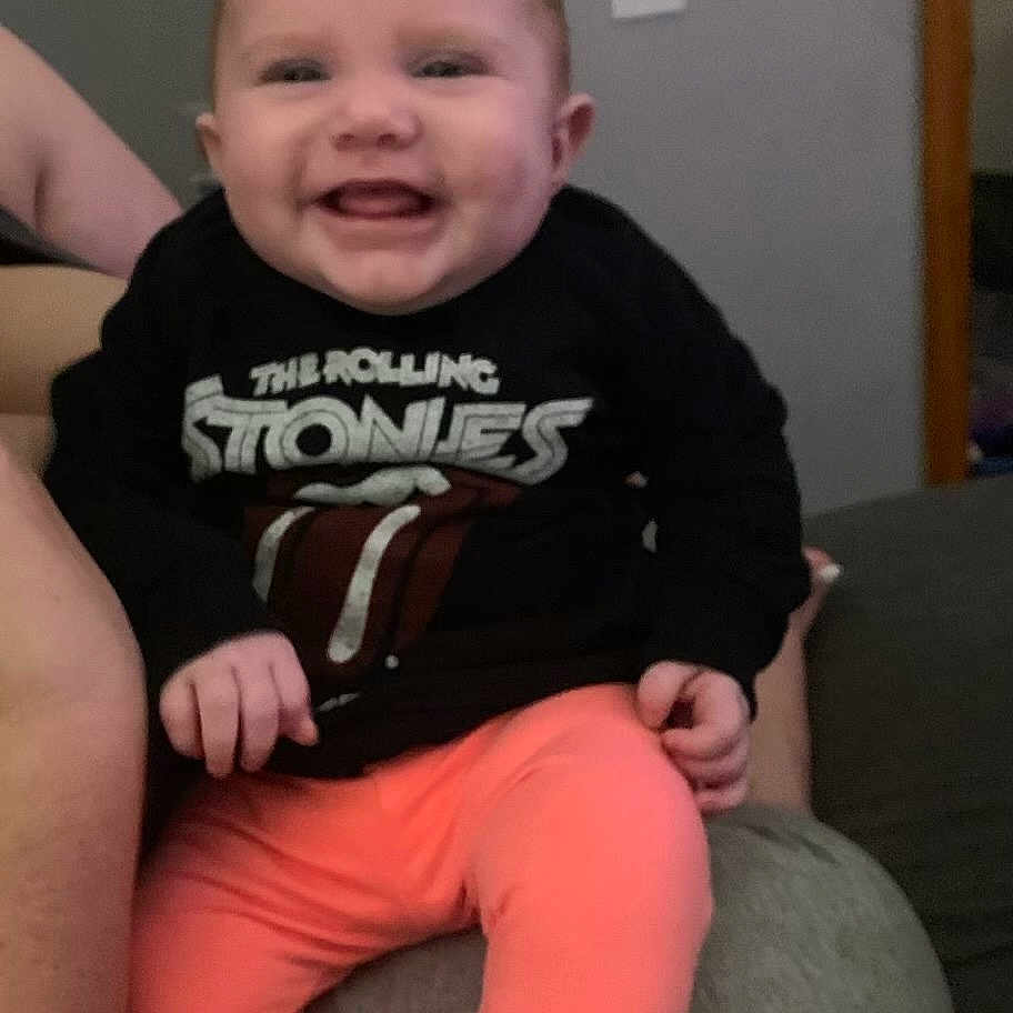 Harleigh is registered to the contest to win money with this photo: baby, bodypart, clothing, couch, cushion, face, furniture, happy, head, homedecor, laughing, mouth, pants, person, photography, portrait, shorts, sitting, t_shirt, teeth