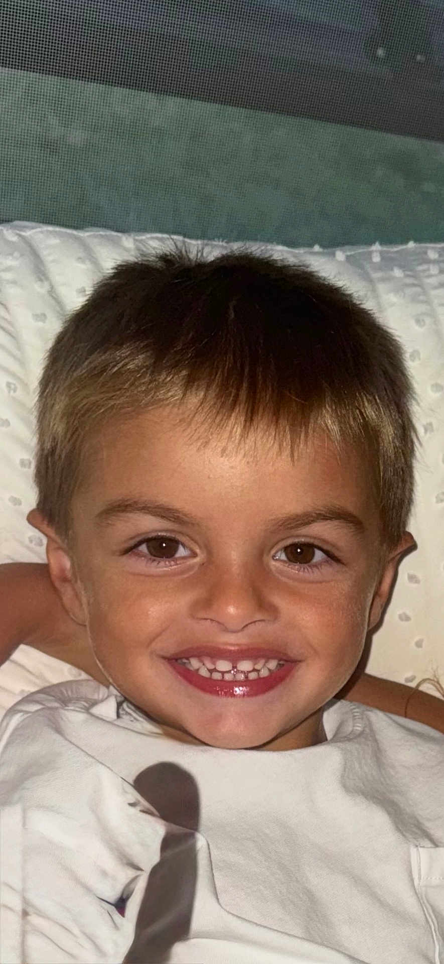 Isaac a rejoint le concours — aidez-le/la à gagner de superbes lots ! child, smile, boy, face, teeth, brown_eyes, hair, pillow, white_shirt, happy, portrait, closeup, indoors, childhood, cute, young, skin, head, expression, person