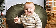 Aksel a rejoint le concours — aidez-le/la à gagner de superbes lots ! baby, infant, child, smile, christmas, holiday, wreath, ornament, presents, gift, christmas_tree, cushion, sweater, corduroy_pants, wooden_floor, portrait, indoor, festive, sitting, studio_backdrop