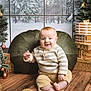 baby, infant, child, smile, christmas, holiday, wreath, ornament, presents, gift, christmas_tree, cushion, sweater, corduroy_pants, wooden_floor, portrait, indoor, festive, sitting, studio_backdrop