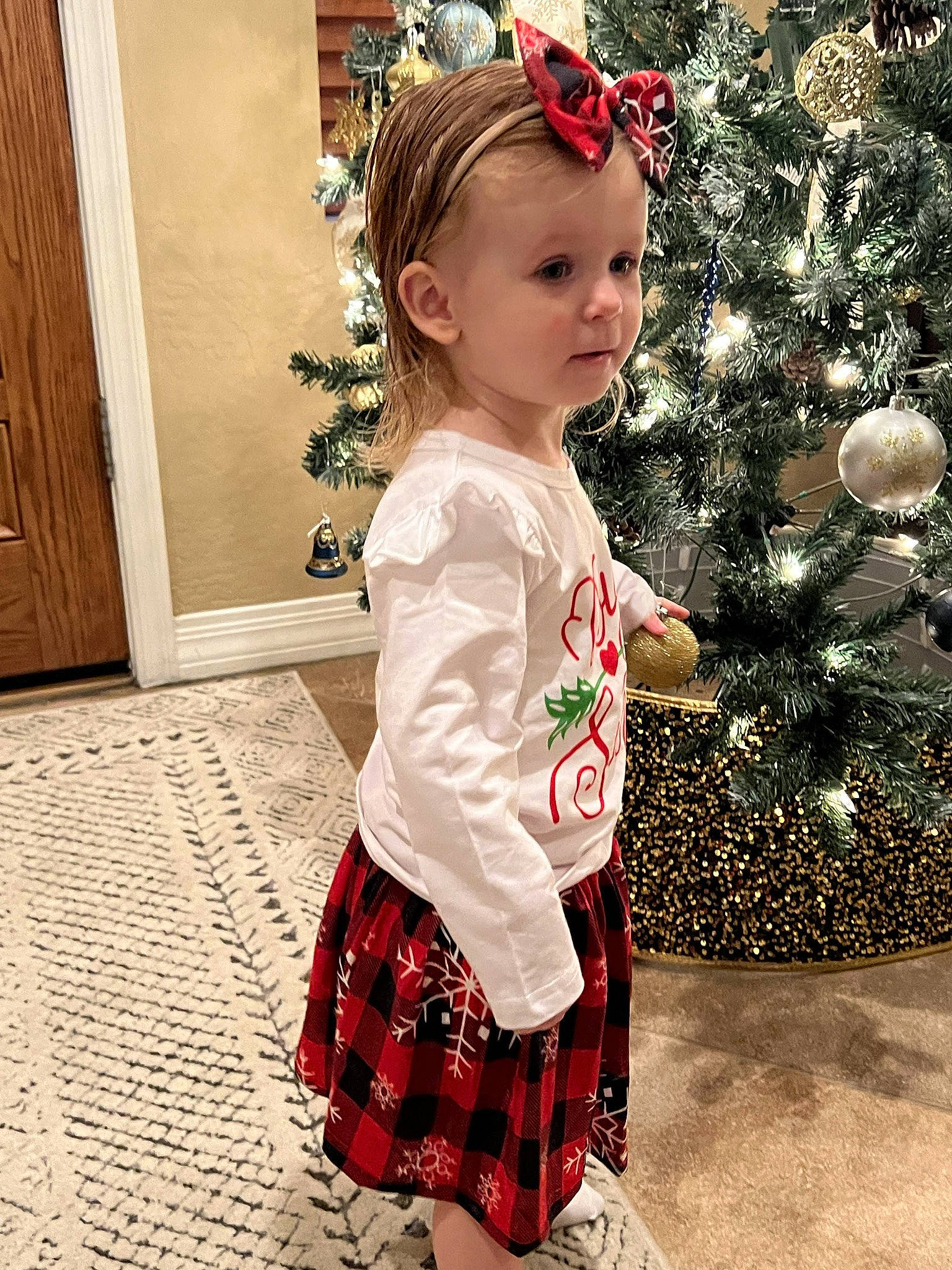 Paige is registered to the contest to win money with this photo: baby_toddler_clothing, cabinetry, child, christmas, christmas_decoration, christmas_tree, day_dress, door, event, happy, holiday, pattern, person, plaid, red, sleeve, snapshot, standing, tartan, toddler