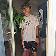 Loris participe au concours pour gagner de l'argent avec cette photo : teenager, child, doorway, curly_hair, tshirt, shorts, indoor, plant, floor_tiles, barefoot, baby_gate, reflection, bracelets, phone, shadow, window, door, pink_dress, person, casual