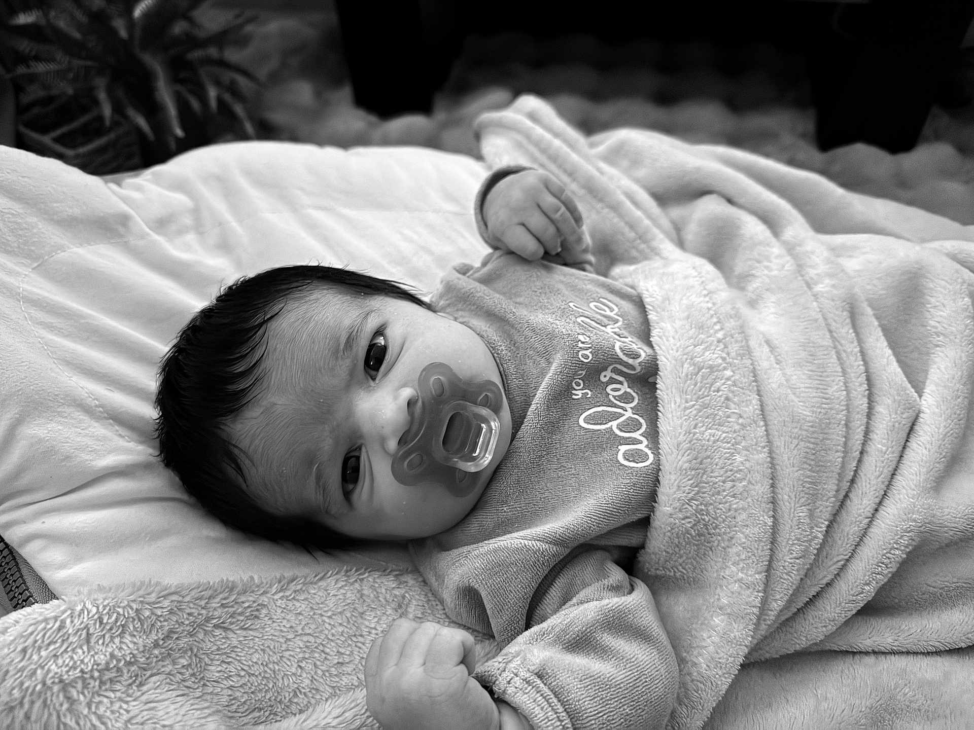 Ada participe au concours pour gagner de l'argent avec cette photo : baby, infant, blanket, pacifier, clothing, face, head, soft_texture, bed, sleepwear, newborn, cute, portrait, lying_down, indoors, comfort, peaceful, baby_bib, black_and_white, young_child