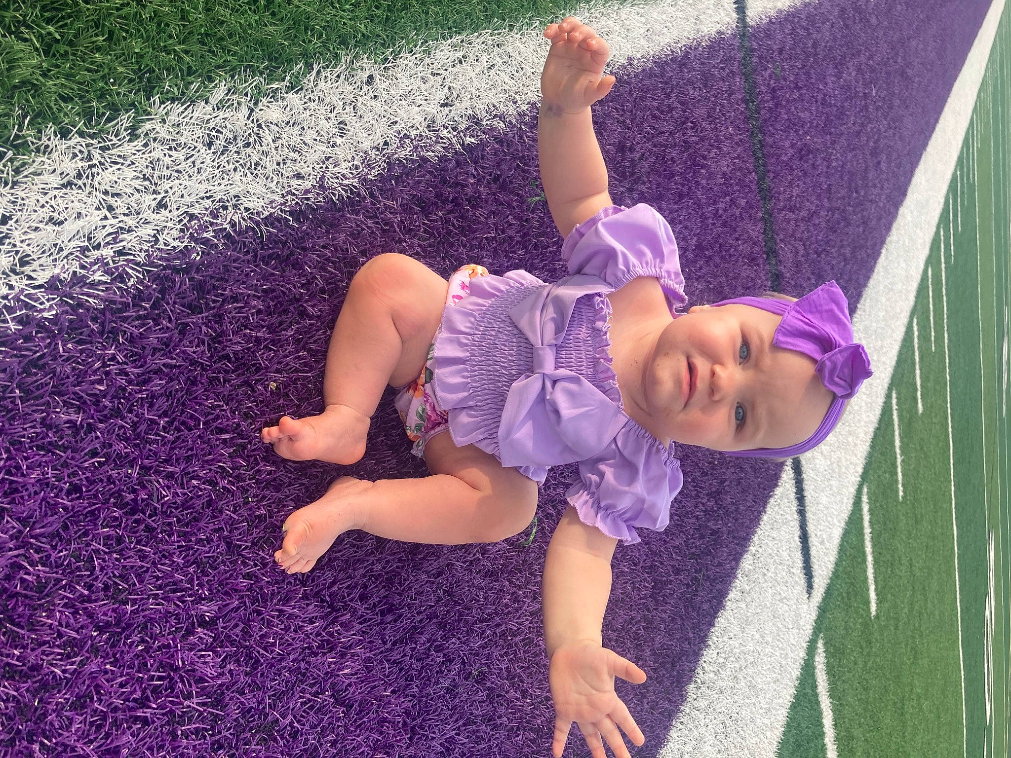 Tessa joined the competition — help win amazing prizes! barefoot, child, flooring, foot, fun, grass, happy, human_leg, knee, leisure, magenta, people_in_nature, person, pink, plant, purple, shadow, sitting, thigh, toddler