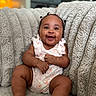 baby, smiling, happy, infant, sitting, couch, plush, textured, hair_ties, cute, indoors, cozy, child, person, skin, clothing, room, furniture, portrait, relaxed