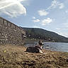 Balou a rejoint le concours — aidez-le/la à gagner de superbes lots ! dog, sand, water, lake, stone_wall, sky, clouds, mountains, outdoor, sunny, nature, beach, leash, calm, relaxing, daytime, scenic, animal, pet, landscape