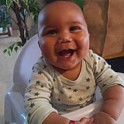 Wesley participe au concours pour gagner de l'argent avec cette photo : baby, smiling, high_chair, happy, indoor, child, face, hands, clothing, bracelet, furniture, plant, home, person, portrait, cute, infant, star_pattern, table, seat