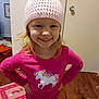 architecture, art, beanie, bonnet, building, cap, child, clothing, face, female, furniture, girl, hardwood, hat, head, indoors, livingroom, painting, person, wood