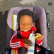 Djayhïlone a rejoint le concours — aidez-le/la à gagner de superbes lots ! baby, child, clothing, cookie, curly_hair, daylight, face, food, happy, milk_bottle, outdoor, pavement, person, red_jacket, seatbelt, smiling, snack, stroller, sunlight, toddler