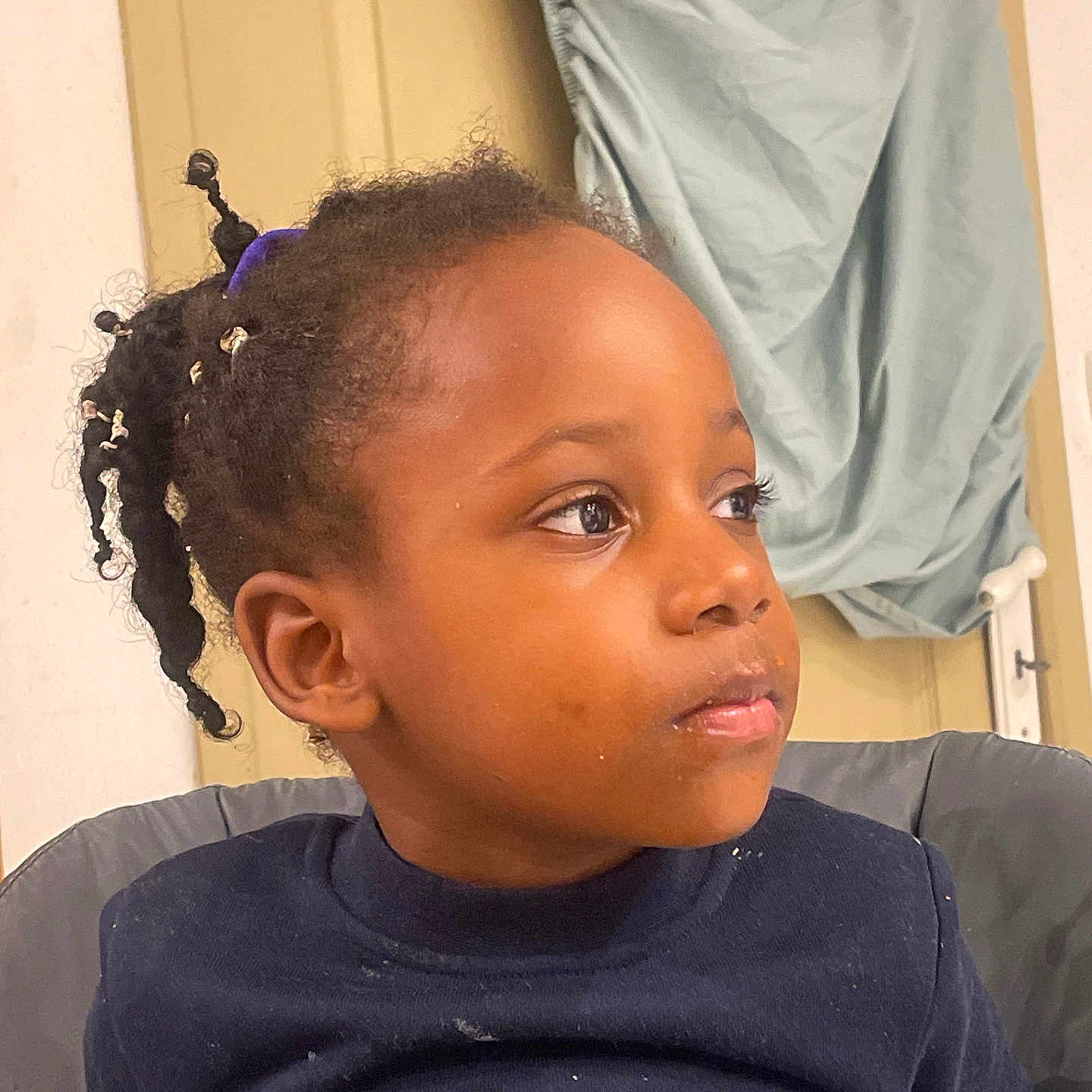 Djayhïlone participe au concours pour gagner de l'argent avec cette photo : background, beads, child, clothing, crumbs, curly_hair, door, expression, fabric, face, hair, head, indoor, looking_away, person, portrait, seated, skin, sweater, young