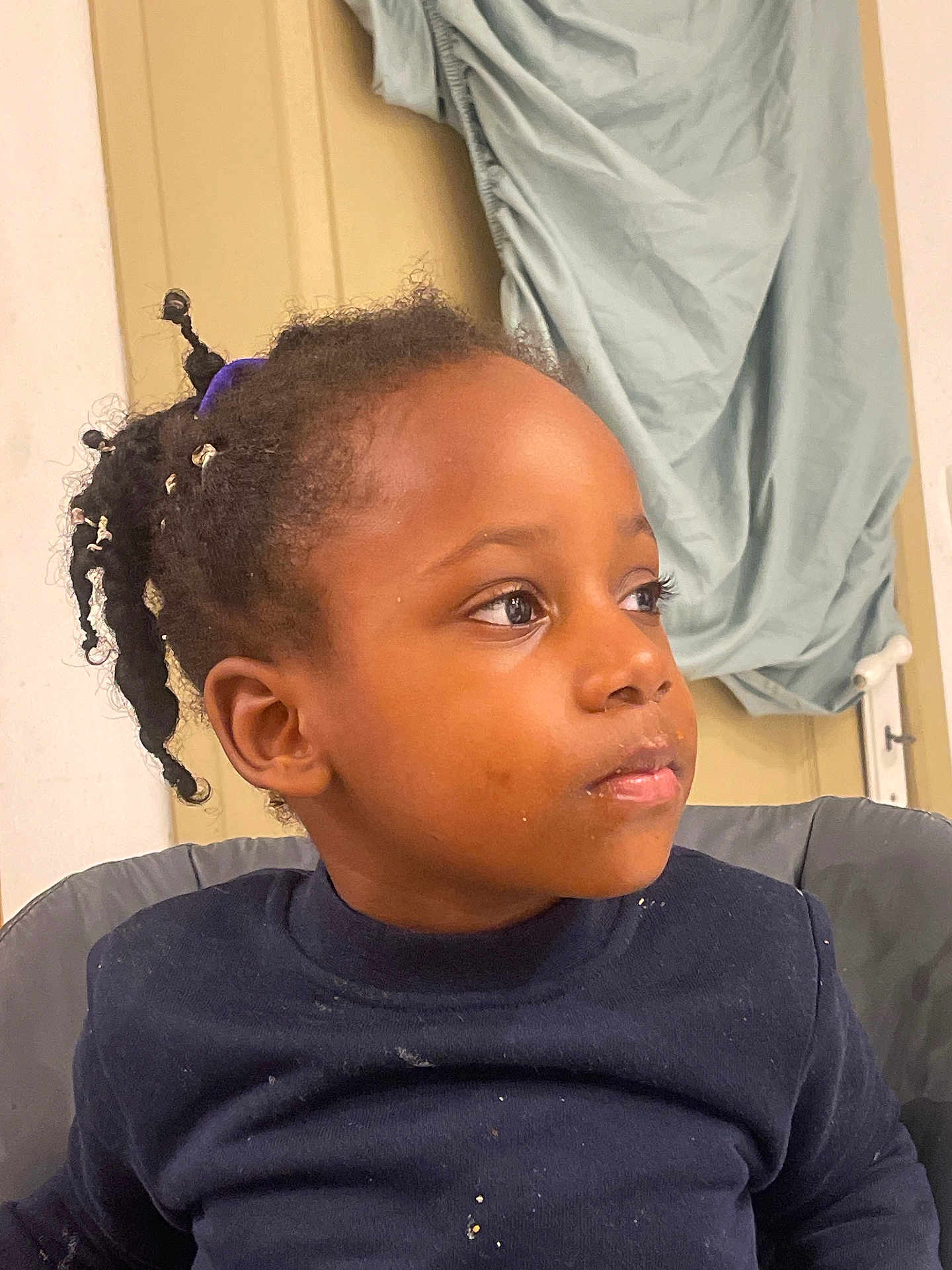 Djayhïlone participe au concours pour gagner de l'argent avec cette photo : background, beads, child, clothing, crumbs, curly_hair, door, expression, fabric, face, hair, head, indoor, looking_away, person, portrait, seated, skin, sweater, young