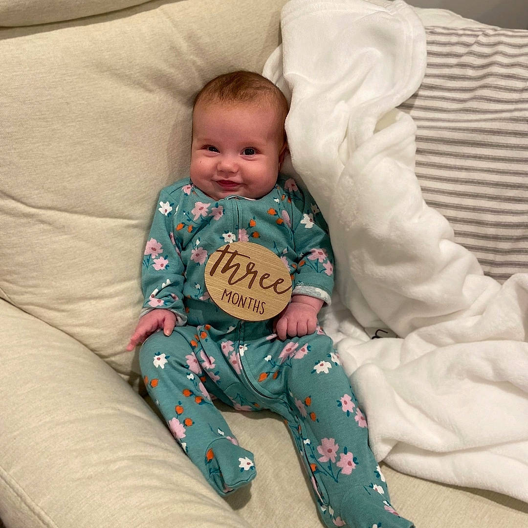 Olivia is registered to the contest to win money with this photo: arm, baby, baby_products, baby_sleeping, baby_toddler_clothing, bedtime, cheek, child, comfort, couch, face, happy, joy, linens, mammal, person, sitting, sleeve, smile, sock