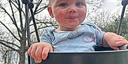 Leighton joined the competition — help win amazing prizes! baby, child, swing, playground, outdoor, trees, sky, black_swing, clothing, cute, happy, person, infant, holding, park, nature, face, hands, curly_hair, rosy_cheeks