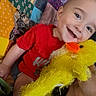 Kaizen joined the competition — help win amazing prizes! baby, bright_colors, child, cozy, cute, face, hand, happy, indoor, patchwork, person, playful, plush_toy, quilt, red_shirt, sitting, smiling, soft_toy, toddler, yellow_duck