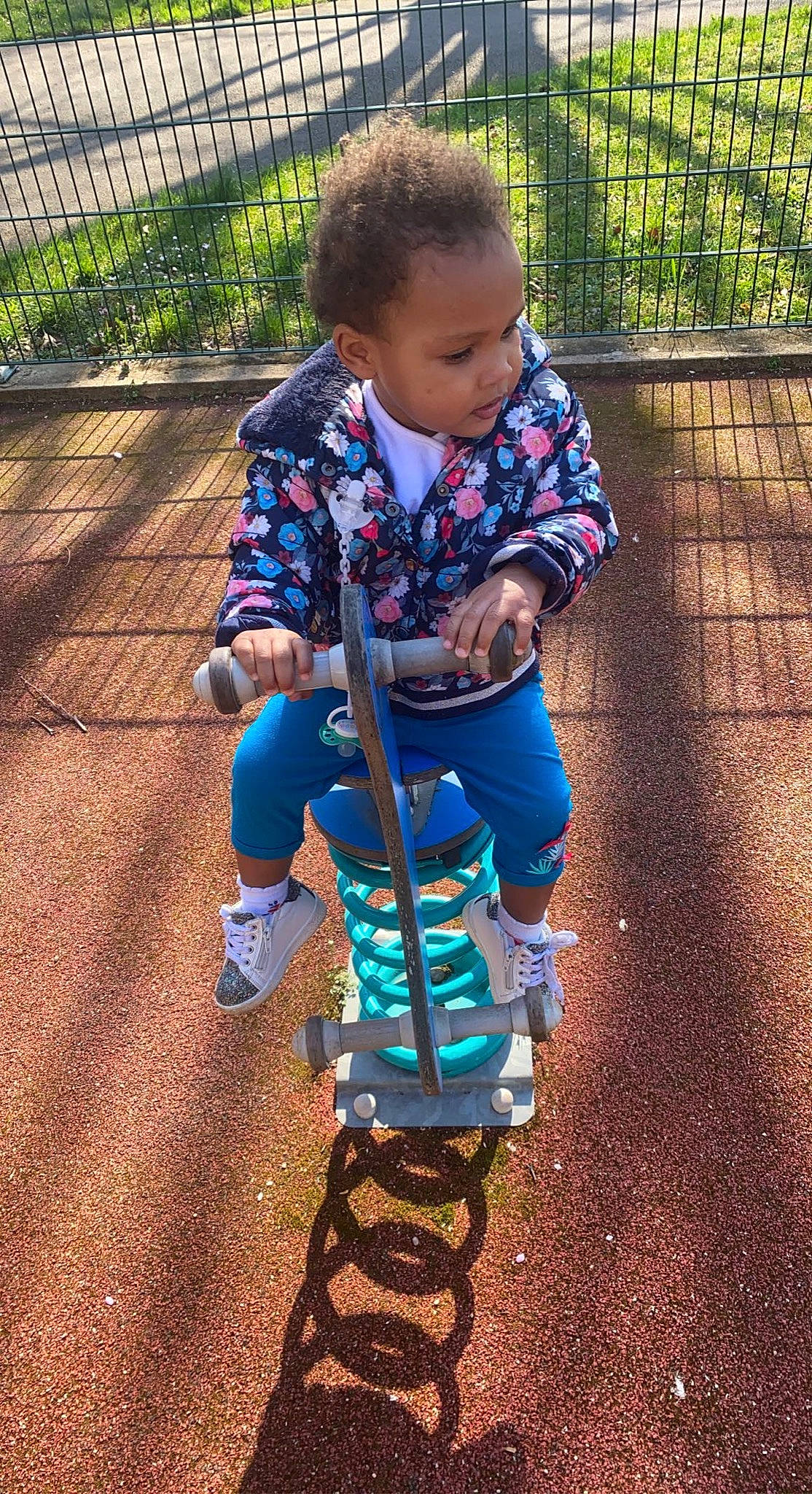 Noëlla participe au concours pour gagner de l'argent avec cette photo : asphalt, baby, baby_products, city, electric_blue, fence, grass, green, leisure, outdoor_play_equipment, people_in_nature, person, plant, playground, recreation, sneakers, swing, tire, toddler, tree