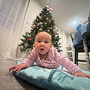 Gabrielle a rejoint le concours — aidez-le/la à gagner de superbes lots ! baby, infant, christmas_tree, holiday_decorations, pink_clothing, blue_mat, floor, home_interior, curtains, table, chair, plant, window, lights, ornaments, star, candy_cane, heart_ornament, person, cute