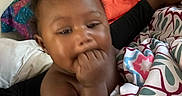 Jaziriah is registered to the contest to win money with this photo: baby, bed, blanket, child, colorful, comfort, cute, face, fingers, hand, indoors, infant, pattern, person, pillow, portrait, resting, skin, sleepwear, young
