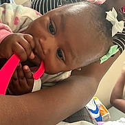 Jaziriah joined the competition — help win amazing prizes! arm, baby, candid, casual, chewing, child, childhood, closeup, family, focus, hair_bow, hand, happy, indoor, infant, person, playing, skin, striped_clothing, toy