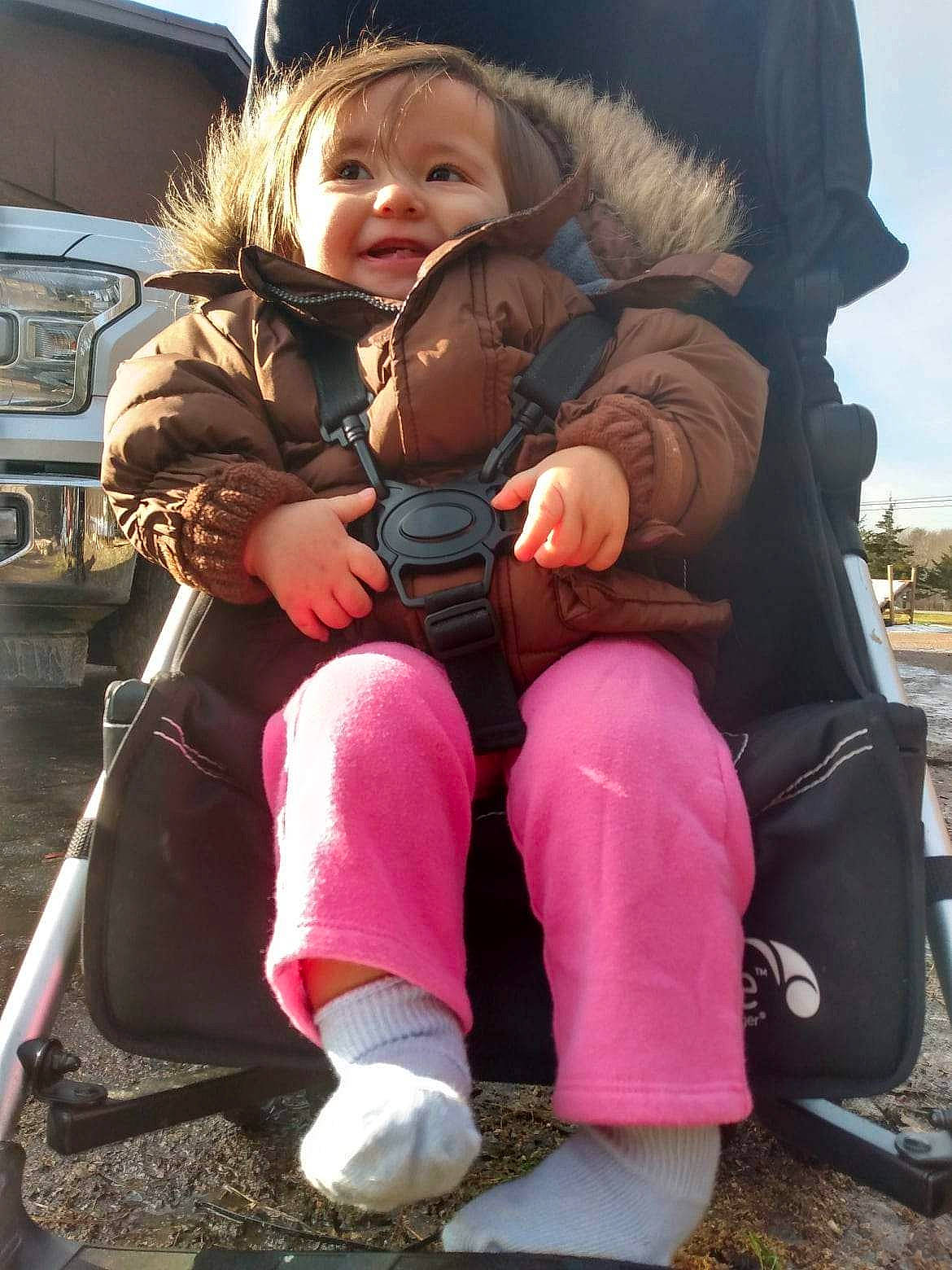 Ayla is registered to the contest to win money with this photo: baby_carriage, baby_products, baby_toddler_clothing, boot, child, comfort, fun, fur, happy, lap, leg, leisure, person, pink, sitting, skin, sky, smile, sneakers, thigh