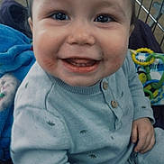 Oliver is registered to the contest to win money with this photo: baby, infant, smiling, face, eyes, teeth, cheeks, sweater, button, toy, teething_ring, shopping_cart, blanket, hand, portrait, close_up, happiness, playful, indoor, metal_grate