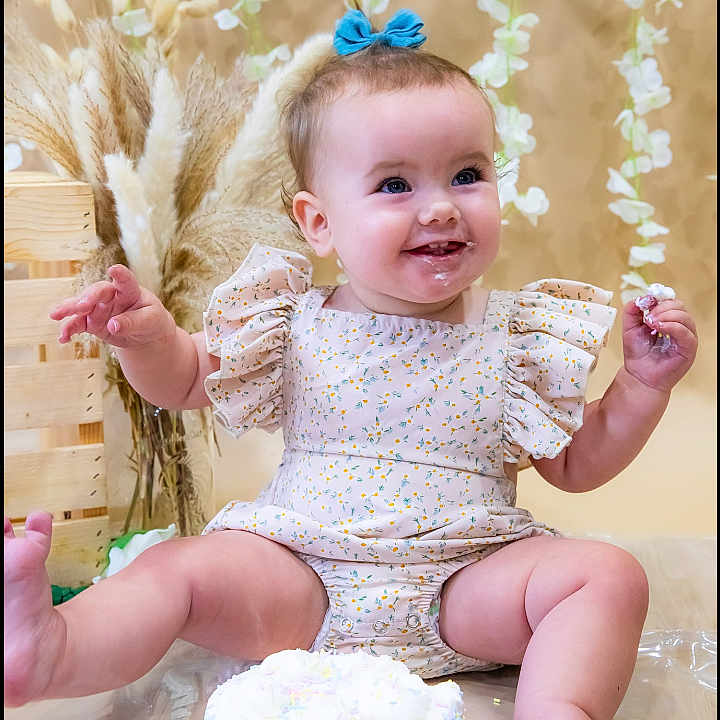 Karyn joined the competition — help win amazing prizes! baby, birthday, blue_bow, cake, celebration, child, colorful_sprinkles, cute, dress, floral_background, fun, happy, indoor, infant, messy_face, pampas_grass, photography, portrait, sitting, smiling