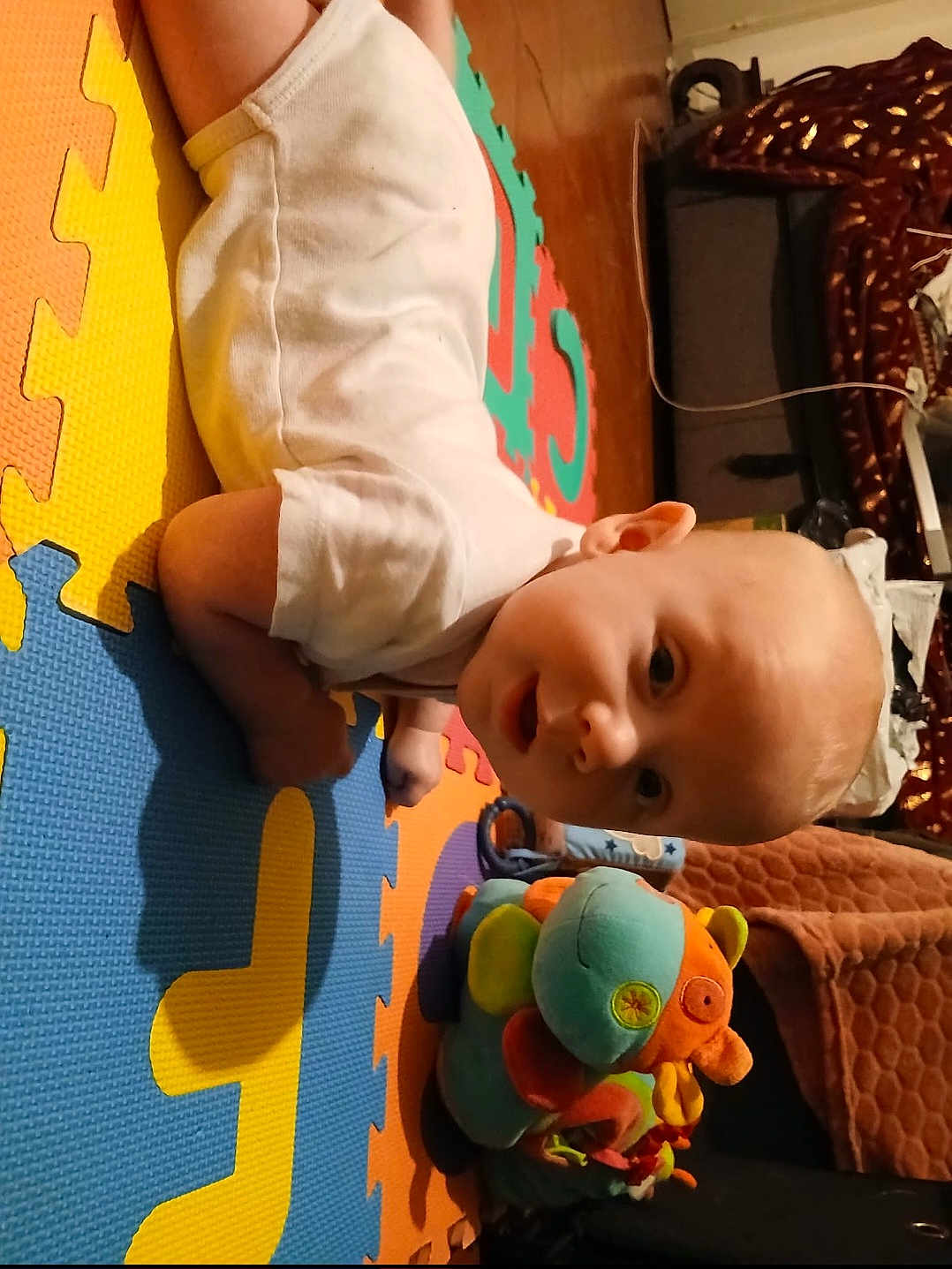 Vojta participe au concours pour gagner de l'argent avec cette photo : baby, child, toy, plush_toy, colorful, foam_mat, floor, indoor, white_clothing, curious, infant, crawling, head, face, play, soft_toy, person, home, puzzle_mat, cute