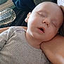 arm, baby, child, closeup, cozy, face, folded_clothes, gray_clothing, indoor, infant, nap, peaceful, person, portrait, relaxed, resting, sleeping, soft_light, tender, water_bottle