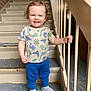 Nicklas joined the competition — help win amazing prizes! toddler, child, smiling, standing, staircase, railing, dinosaur_print, shirt, blue_pants, socks, shoes, brick_wall, urban, rusty, handrail, casual_clothing, young_child, indoor, portrait, happy