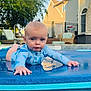 baby, child, swimsuit, water, pool, outdoor, sunlight, backyard, blue, face, crawling, water_droplets, young_child, playful, summer, reflection, tree, fence, chair, house