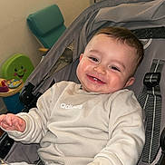 Tariq a rejoint le concours — aidez-le/la à gagner de superbes lots ! baby, infant, stroller, smile, teeth, chubby_cheeks, hand, sweatshirt, adidas_logo, beige_outfit, seat_harness, buckle, toy, playroom, chair, window, indoor, portrait, happy, hair