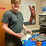 Whisper is registered to the contest to win money with this photo: animal, animal_care, blanket, cat, colorful, door, furniture, hand, happy, indoor, person, pet, poster, resting, room, short_sleeve_shirt, smiling, table, veterinary_office, young_adult