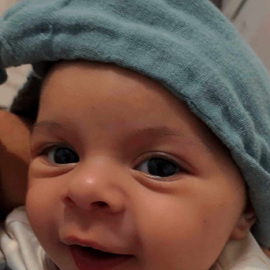 Gabriel participe au concours pour gagner de l'argent avec cette photo : apparel, baby, cheeks, child, close_up, cozy, cute, expression, eyes, face, hat, headwear, indoors, infant, mouth, person, portrait, skin, smiling, warm