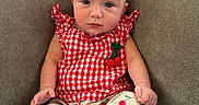 Kailani joined the competition — help win amazing prizes! baby, child, infant, portrait, sitting, couch, indoor, bow, headband, red, gingham, dress, cherries, patterned_clothing, barefoot, face, eyes, expression, furniture, cozy