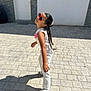 child, girl, sunglasses, white_clothing, outdoor, sunny, shadow, pavement, door, wall, playful_pose, long_hair, casual, fashion, footwear, side_view, summer, smiling, person, daylight