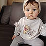 Margot participe au concours pour gagner de l'argent avec cette photo : baby, child, infant, sitting, couch, sweater, winnie_the_pooh, headwear, blue_eyes, curly_hair, rosy_cheeks, indoor, furniture, soft_lighting, person, cute, portrait, clothing, home, comfortable