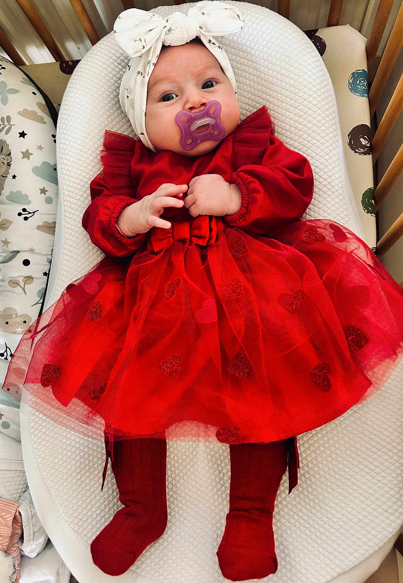 Aélia a rejoint le concours — aidez-le/la à gagner de superbes lots ! baby, infant, pacifier, headband, bow, red_dress, tulle_skirt, heart_pattern, crib, bassinet, mattress, socks, tights, legs, hands, fingers, portrait, cute, sleepy, nursery