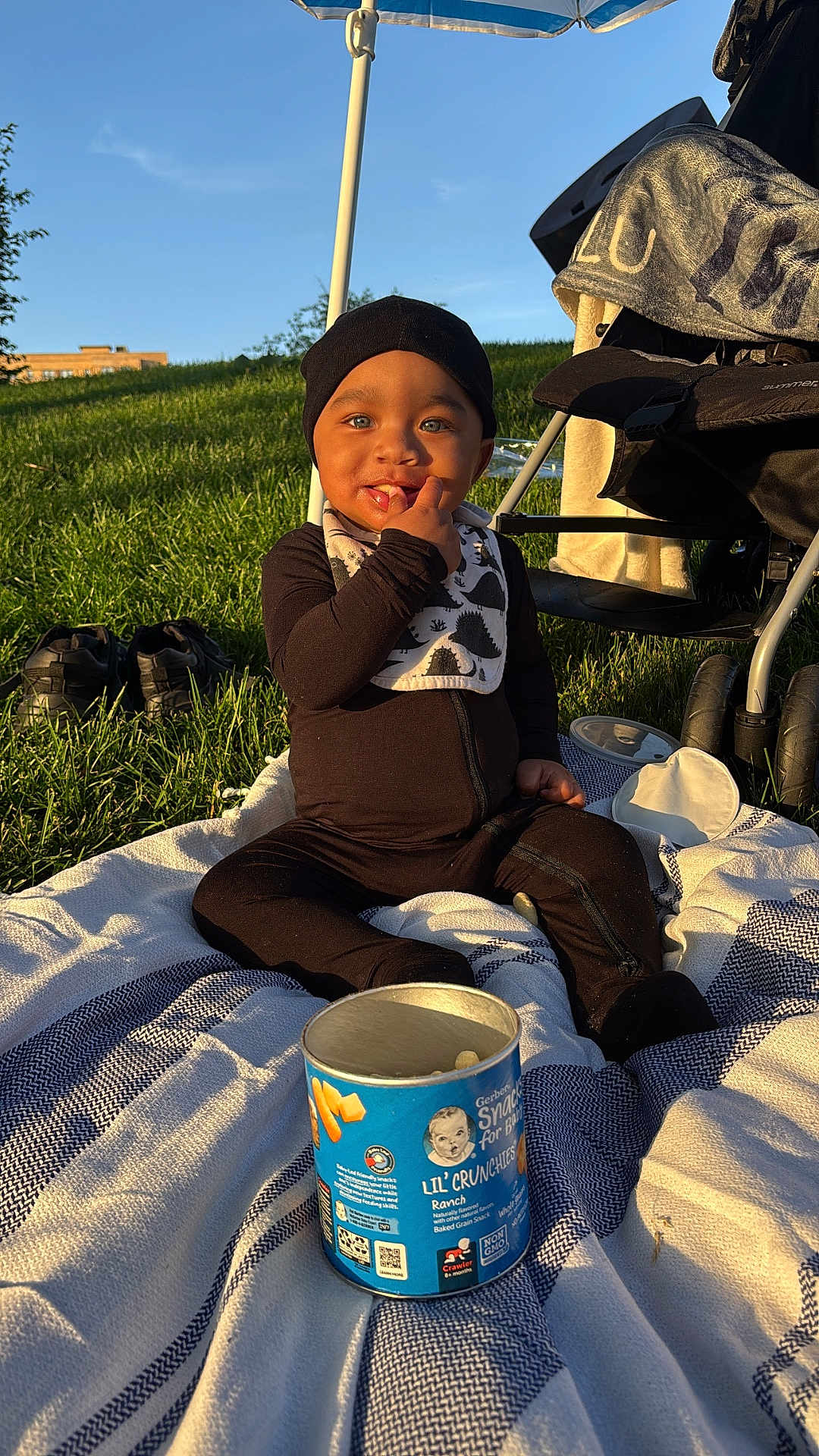 Saint joined the competition — help win amazing prizes! baby, child, snack, blanket, grass, stroller, sunlight, outdoor, blue_sky, hat, bib, shoes, can, person, sitting, smiling, face, toy, playtime, leisure