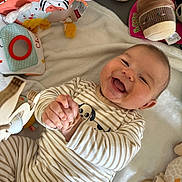 Louis a rejoint le concours — aidez-le/la à gagner de superbes lots ! baby, smiling, striped_pajamas, clapping, plush_toys, soft_blanket, playmat, cute, happy, infant, child, indoors, lying_down, face, hands, cozy, comfort, young, joyful, expression
