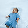 Asaiah is registered to the contest to win money with this photo: baby, infant, child, portrait, lying_down, blue_outfit, romper, blanket, white_background, bed, smiling, happy, face, eyes, hands, feet, indoor, photography, candid, baby_portrait