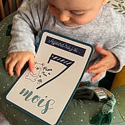 Nino a rejoint le concours — aidez-le/la à gagner de superbes lots ! baby, infant, child, milestone_card, seven_months, grey_clothing, cushion, green, polka_dots, hand, face, sitting, indoors, wooden_bars, soft_lighting, cute, portrait, baby_toys, close_up, baby_boy