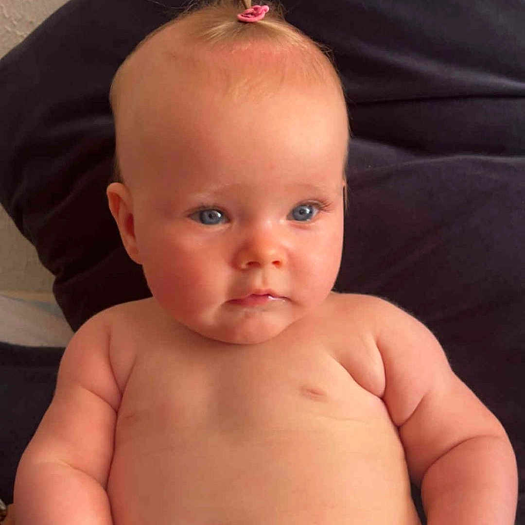 Jade a rejoint le concours — aidez-le/la à gagner de superbes lots ! baby, blue_eyes, child, chubby, cute, diaper, expression, face, hair_tie, hand, head, indoors, infant, person, pillow, portrait, sitting, skin, soft_light, young