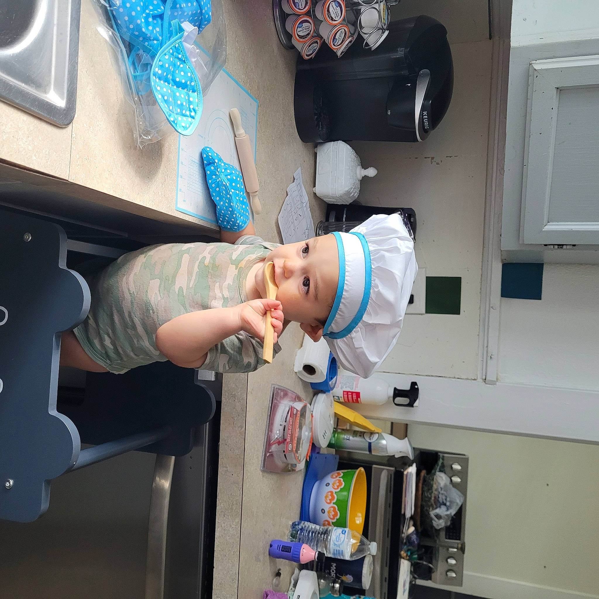 Archer is registered to the contest to win money with this photo: cabinetry, child, fun, gesture, headwear, home_appliance, kitchen, kitchen_appliance, machine, major_appliance, person, refrigerator, room, service, space, t_shirt, toddler