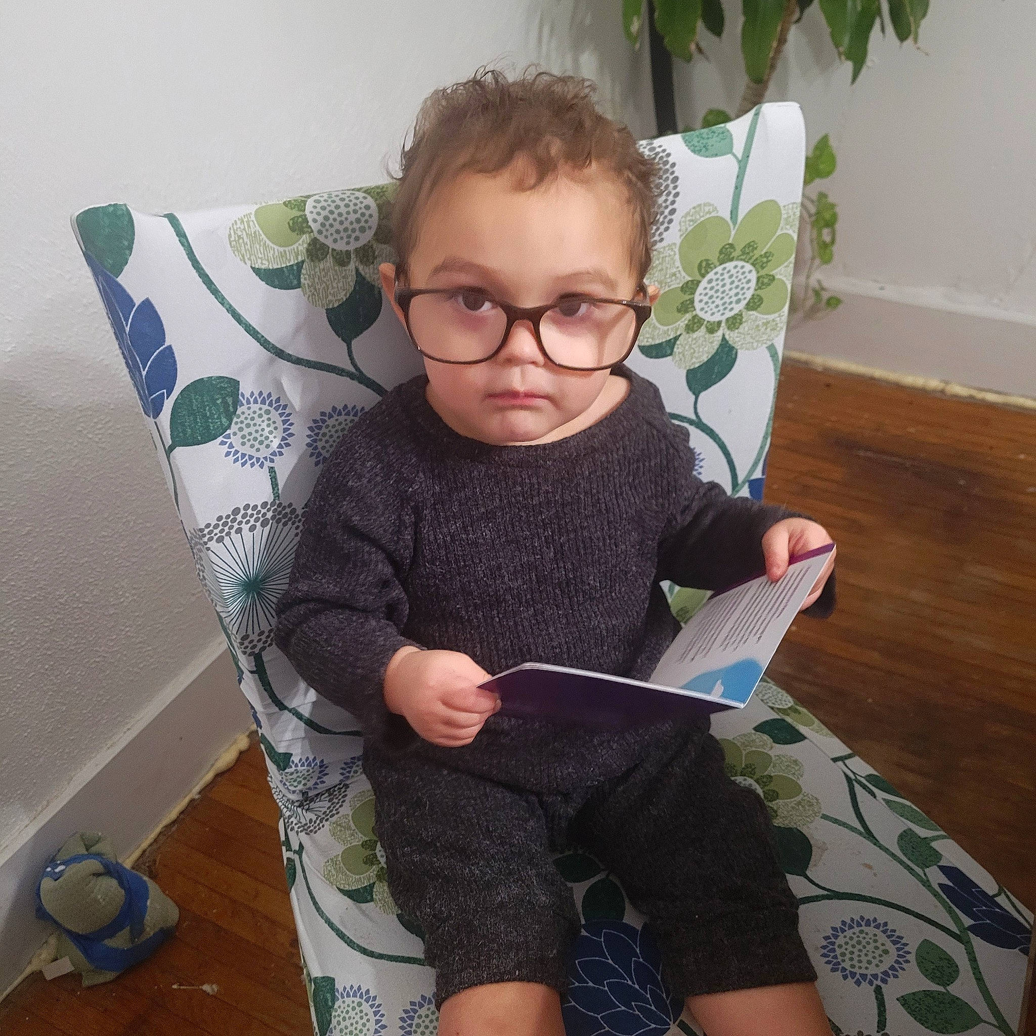 Archer is registered to the contest to win money with this photo: baby_toddler_clothing, barefoot, child, comfort, eyewear, flooring, glasses, happy, human_leg, knee, lap, pattern, person, play, sitting, sleeve, sock, t_shirt, thigh, toddler